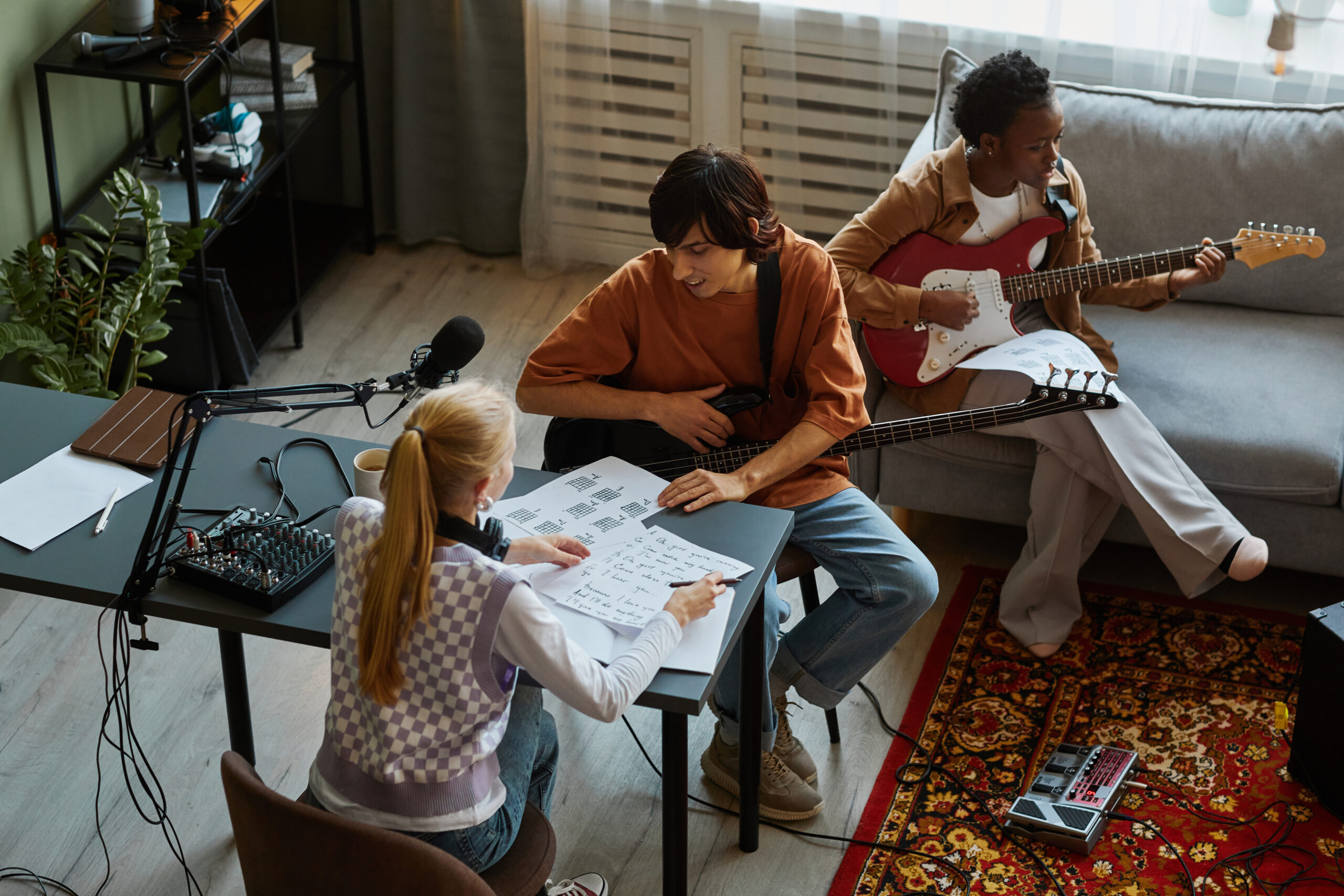 High angle view of young musicians writing songs together and playing musical instruments in studio
